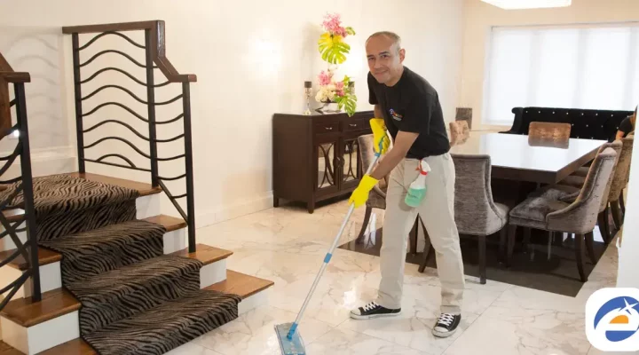 Professional house cleaner mopping the floor in a modern living room with stylish furniture and decor
